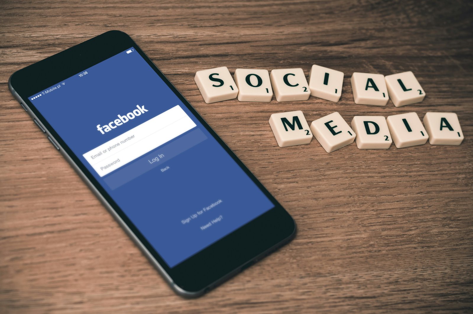 Smartphone displaying Facebook with dice spelling out 'SOCIAL MEDIA' in the background